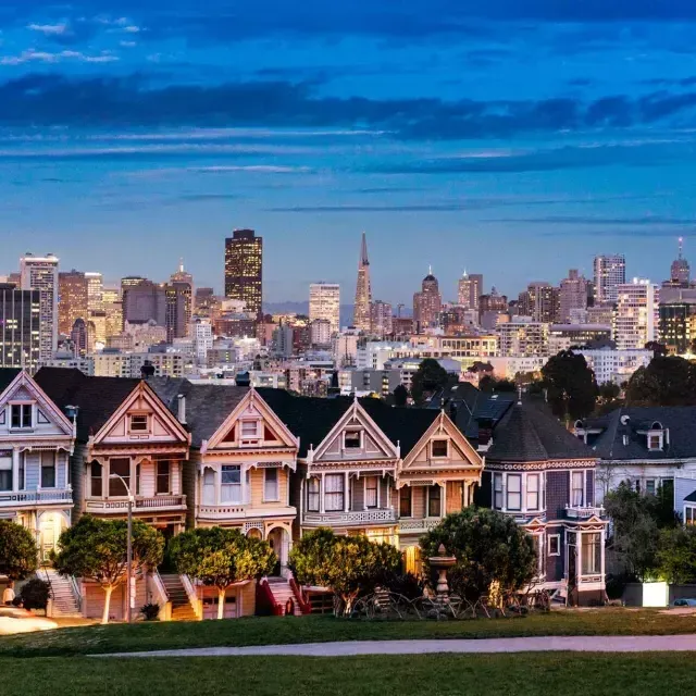 The famous Painted Ladies of Alamo Square are pictured before the San Francisco skyline at twilight.